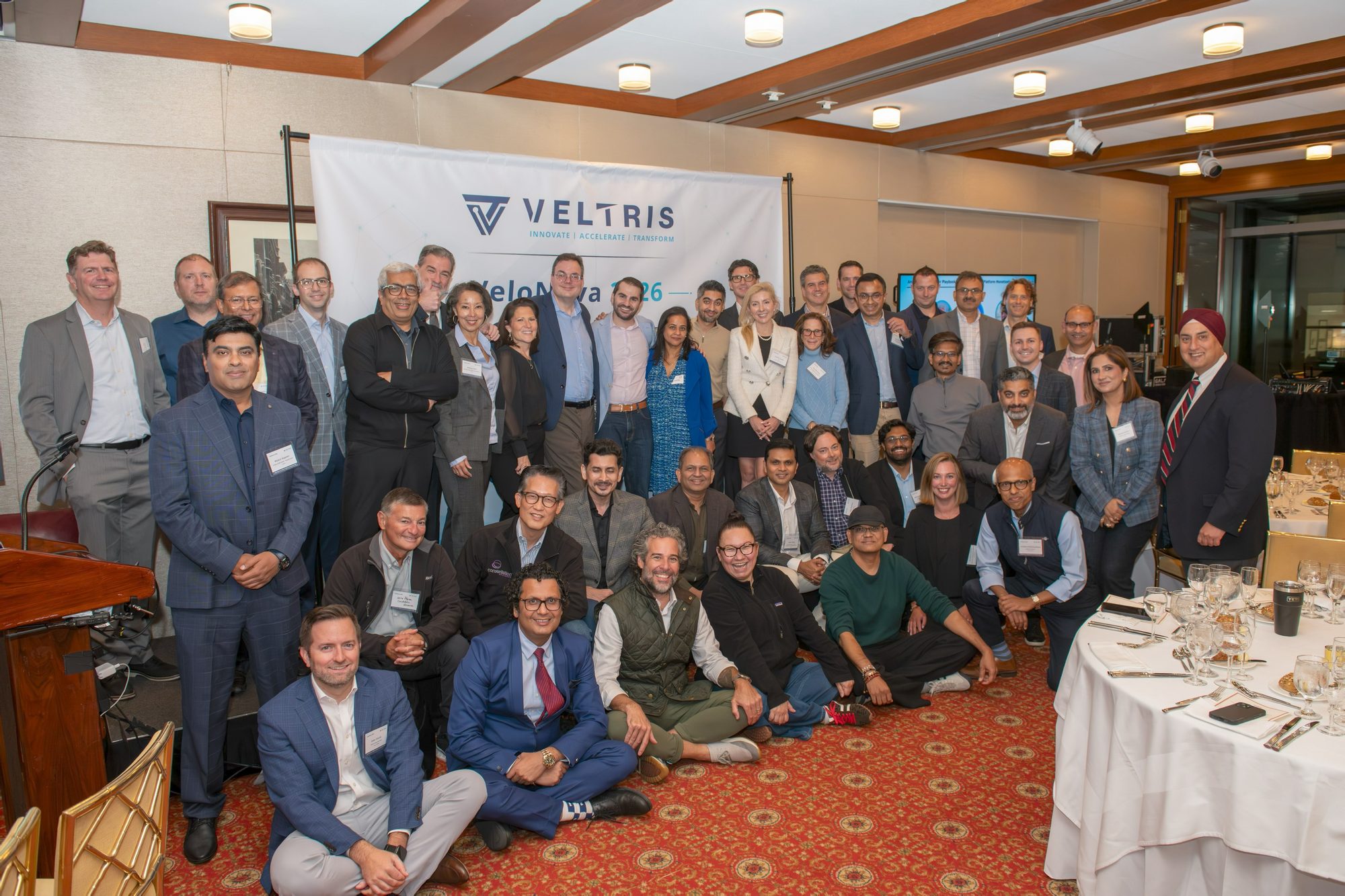 VeloNova 2026 attendees together for a group photograph in front of the Veltris banner